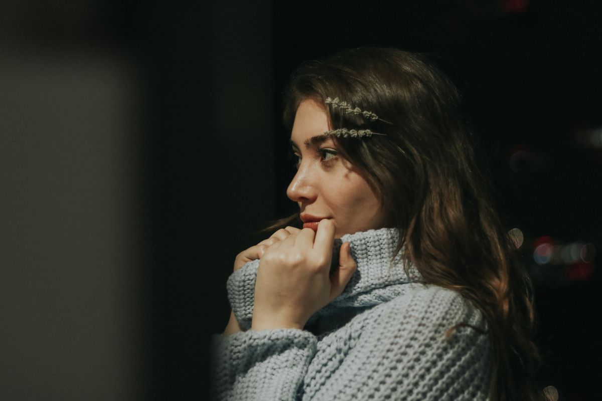 Frau mit langen Haaren und Haarschmuck trägt grob gestrickten Pullover und schaut nach rechts